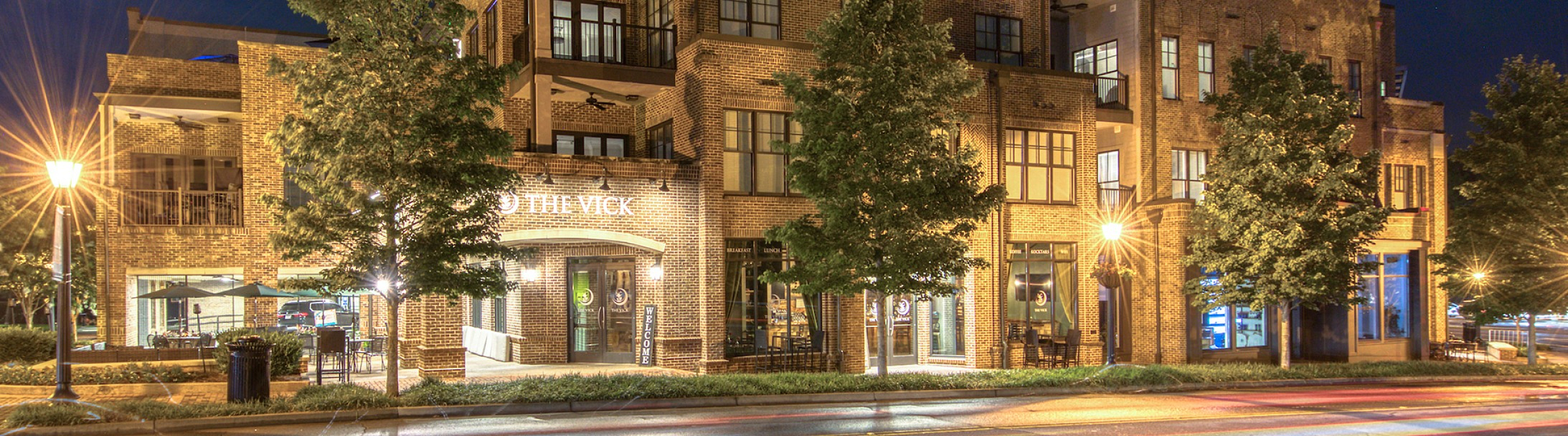 Charming brick apartment building illuminated at night with scenic street view.