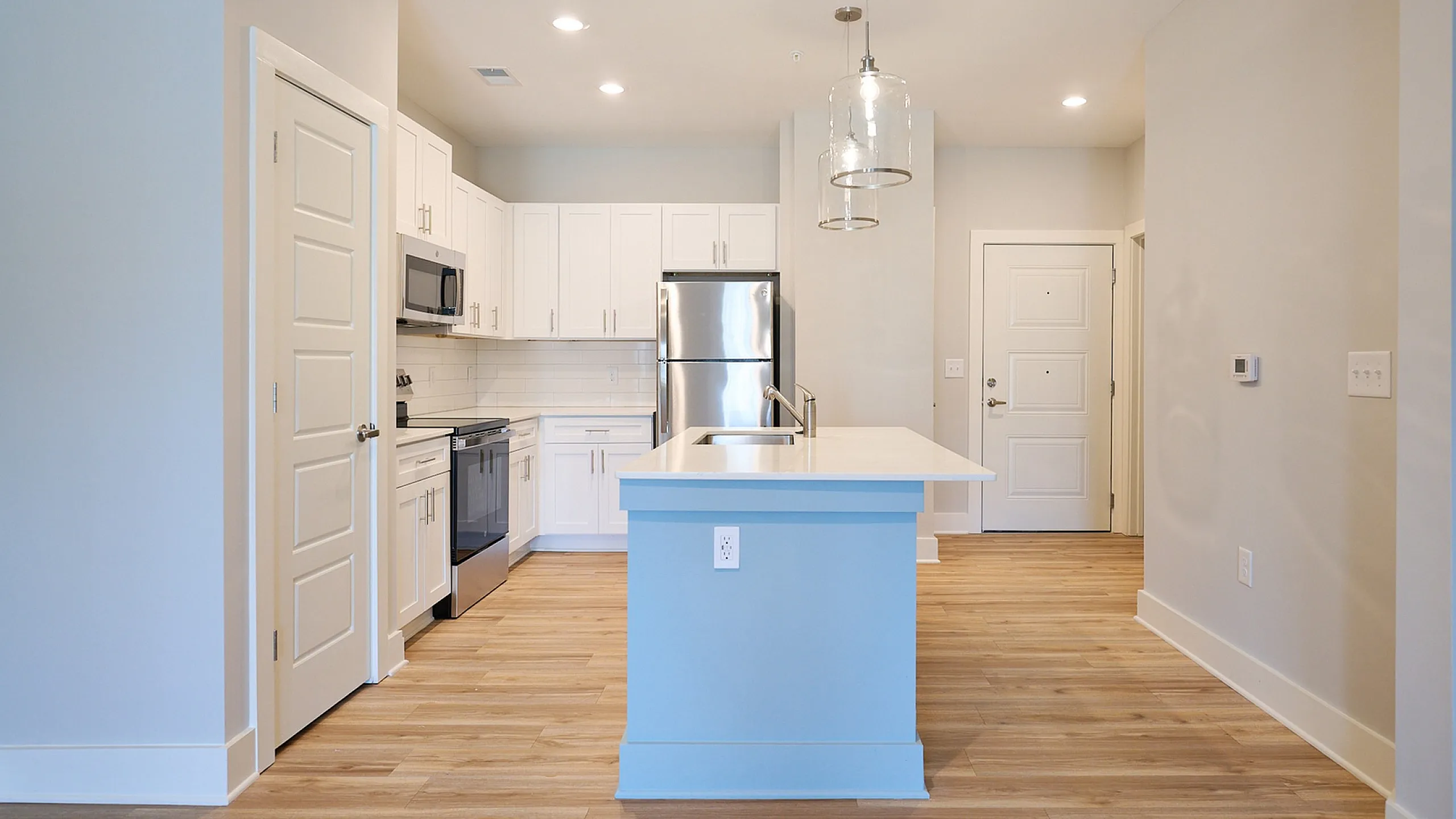 Contemporary kitchen with white cabinets, stainless steel appliances, and a stylish island with pendant lighting.