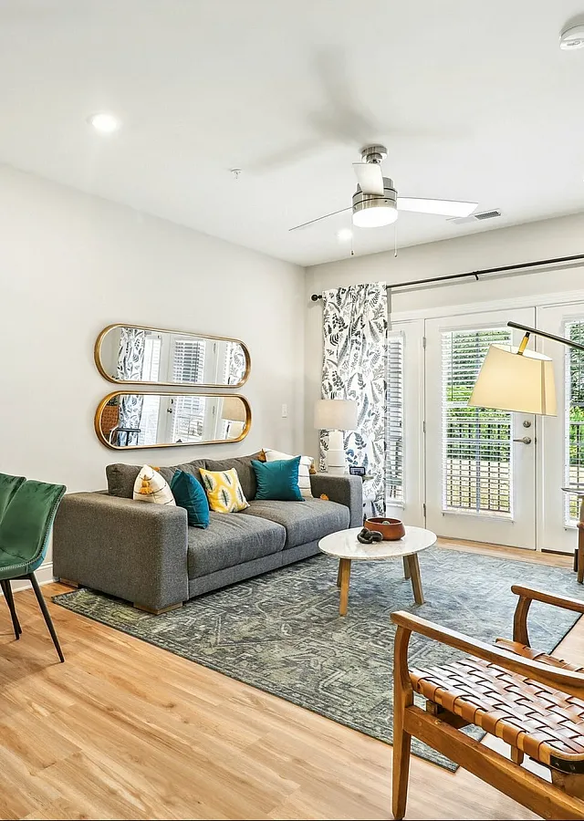 Stylish living room with modern decor, featuring a cozy gray sofa, wooden accents, and vibrant green and blue furnishings.