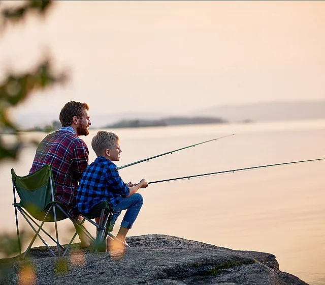 Serene lakeside setting with two people fishing at sunset.
