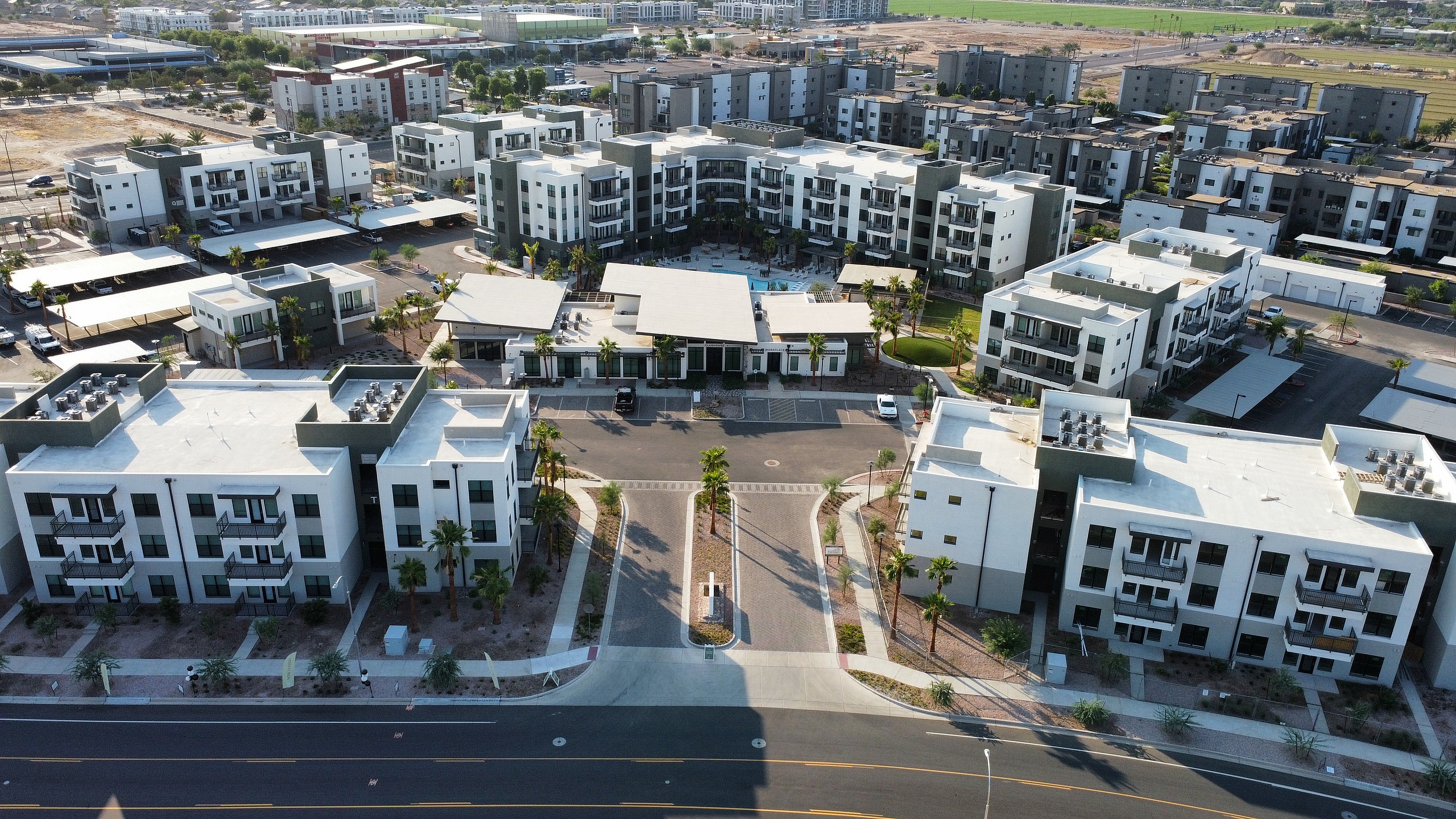 Aerial view of a modern apartment complex with multiple buildings surrounding a central courtyard and pool.