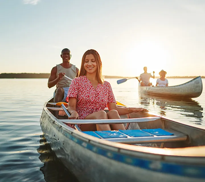 Joyful group canoeing experience on a serene lake at sunset, highlighting adventure and relaxation.