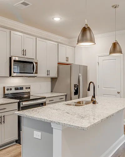 Modern kitchen with elegant granite countertops, sleek stainless steel appliances, and stylish pendant lighting.