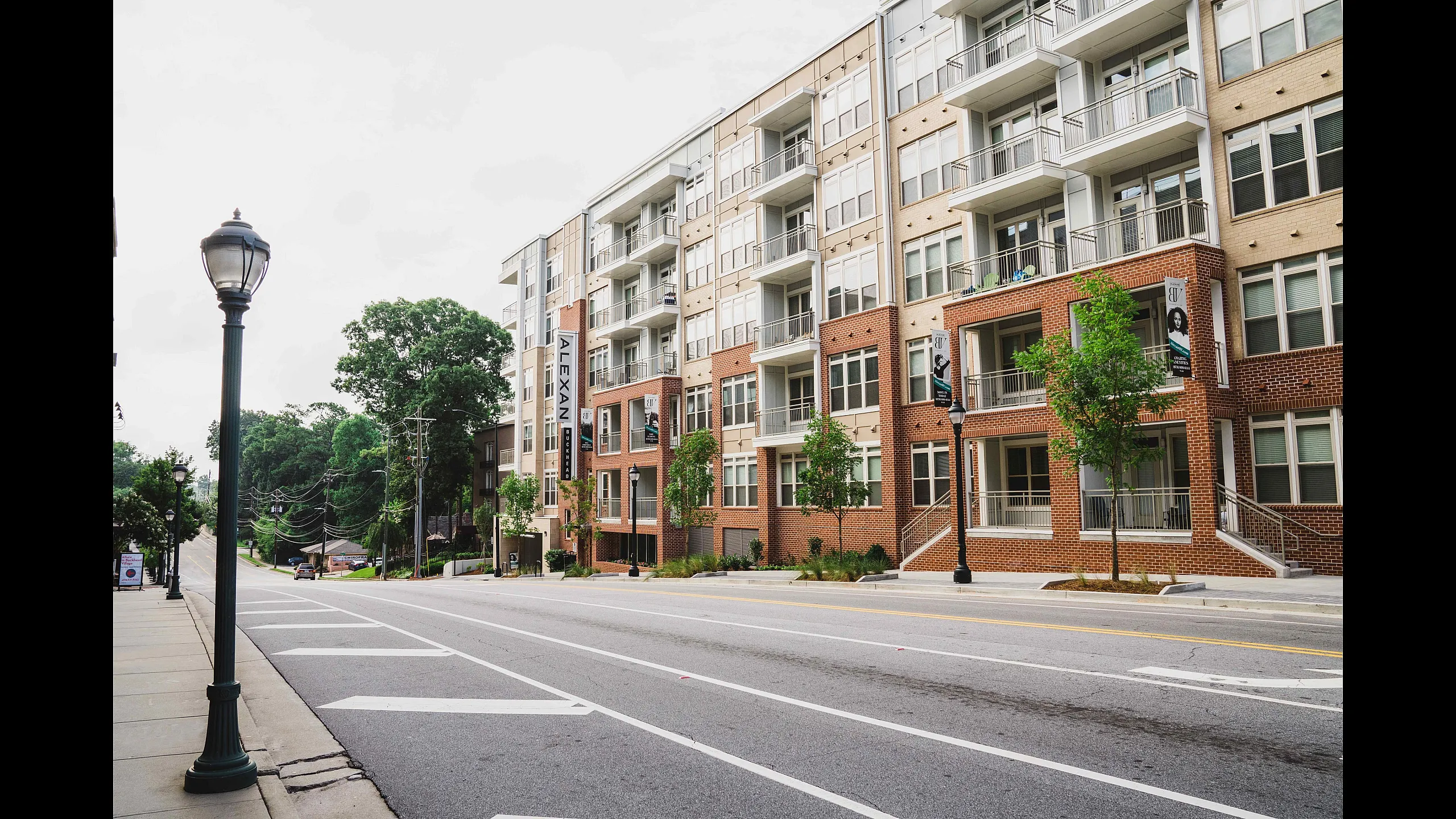 Contemporary apartment complex with spacious balconies, nestled alongside a charming tree-lined street.
