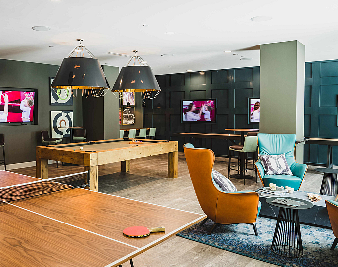 Vibrant recreational lounge featuring a sleek ping pong table, cozy seating with modern chairs, and stylish decor.