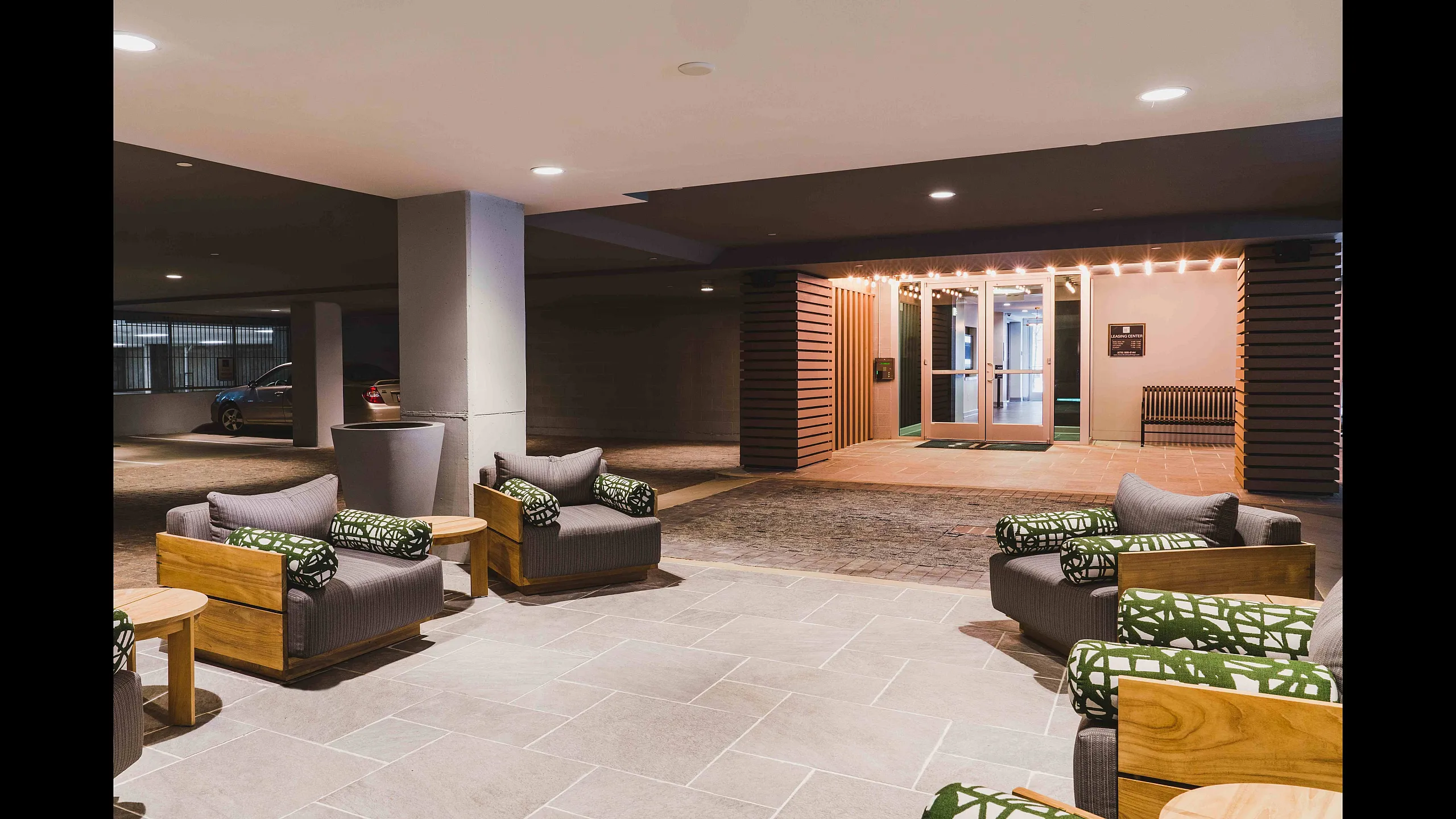Welcoming apartment lobby with modern seating and warm lighting, leading to stylish glass entrance.