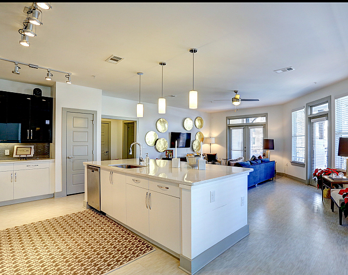 Modern open-concept apartment with a sleek kitchen island, cozy living area, and floor-to-ceiling windows illuminating the space.