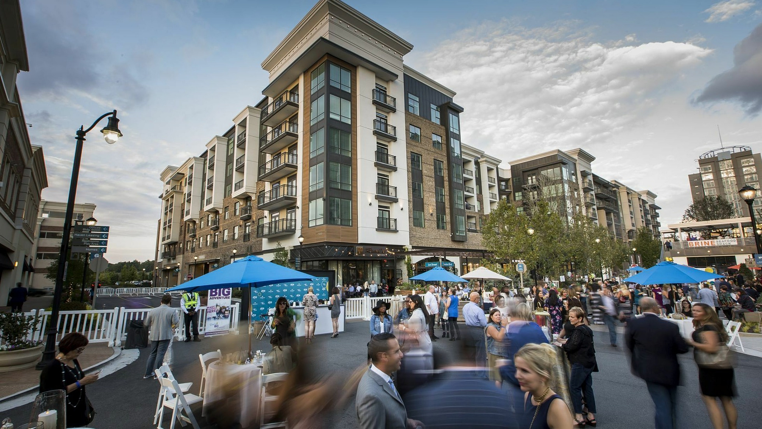 Vibrant urban apartment scene featuring modern architecture, bustling street gathering, and inviting outdoor spaces.
