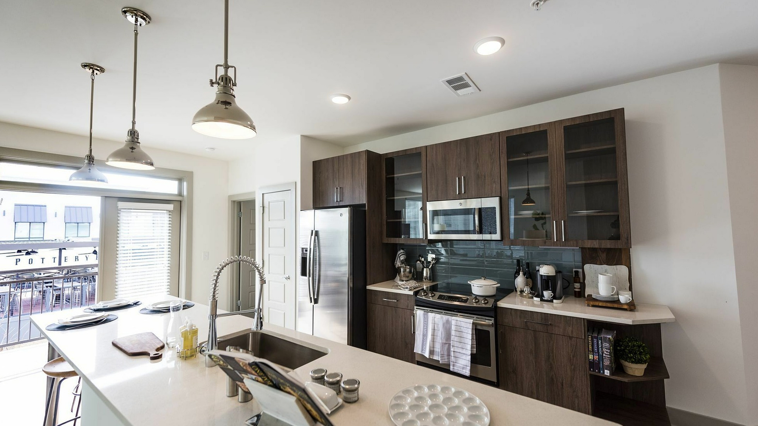 Sleek modern kitchen with stainless steel appliances, open island, and stylish pendant lighting, perfect for entertaining in vibrant apartment living.