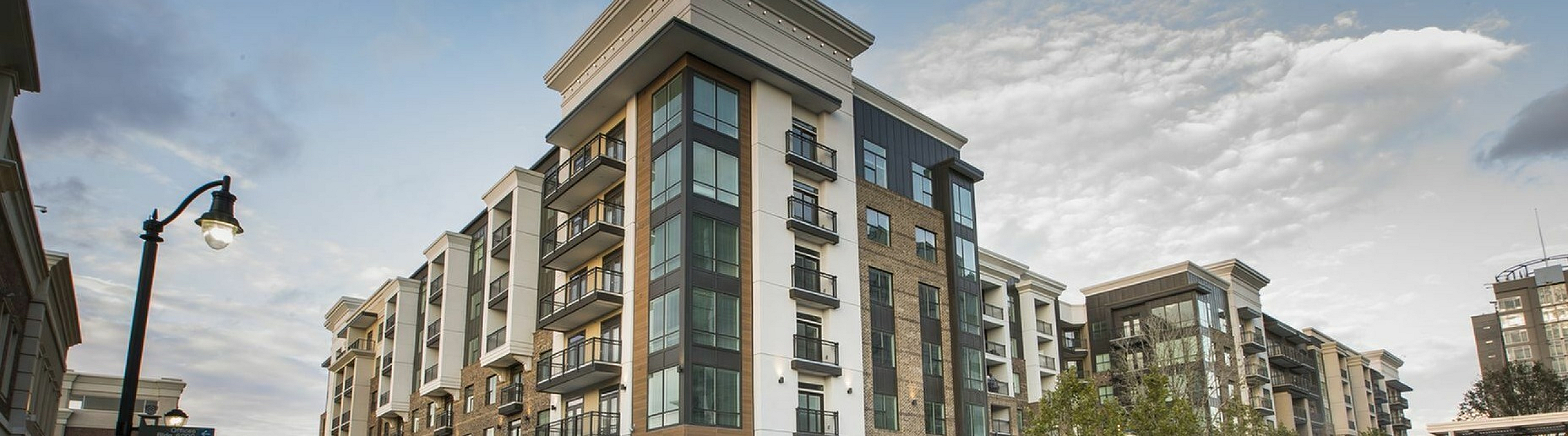Vibrant urban living showcased at a bustling outdoor event in front of modern, stylish apartment buildings with balconies.