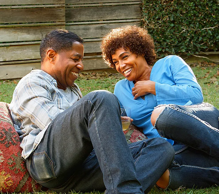 Joyful couple enjoying a relaxing afternoon in a vibrant outdoor garden setting, highlighting a cozy atmosphere and lush greenery.