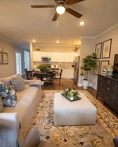 Inviting open-concept living area with elegant decor, featuring a comfortable sofa, stylish dining set, and a modern kitchen with sleek cabinetry.