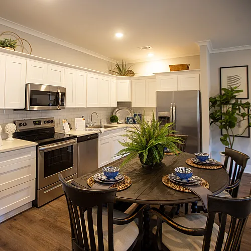 Modern kitchen with sleek white cabinetry, stainless steel appliances, and a charming dining area for cozy meals.