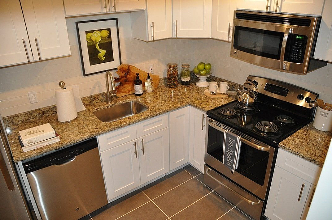 Modern kitchen with sleek stainless steel appliances, elegant granite countertops, and stylish white cabinetry.