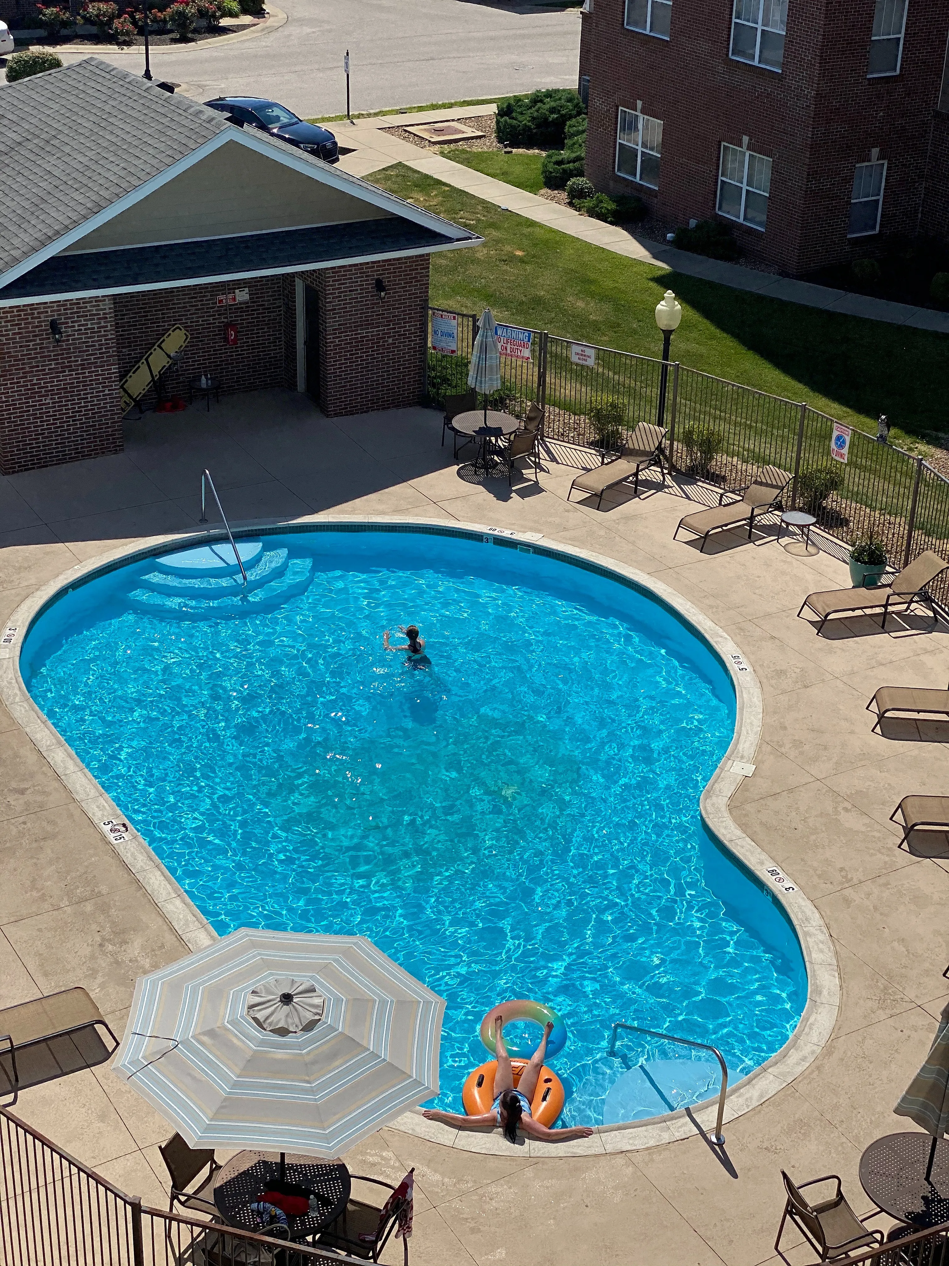 Inviting outdoor pool area with crystal-clear water, surrounded by lounge chairs, umbrellas, and a cozy seating area.