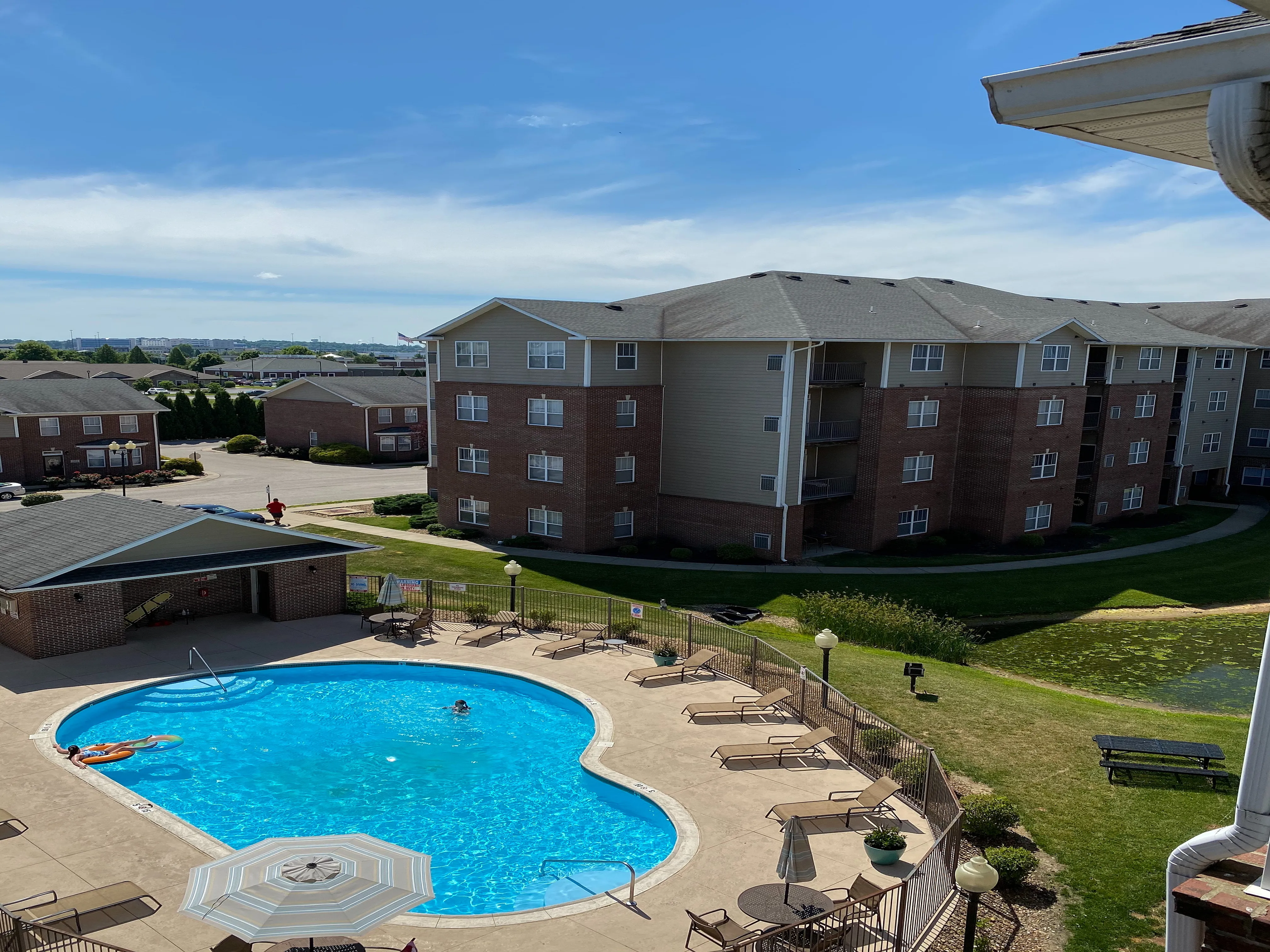 Inviting apartment complex with a refreshing outdoor pool surrounded by lounge chairs, perfect for relaxation and enjoying sunny days.