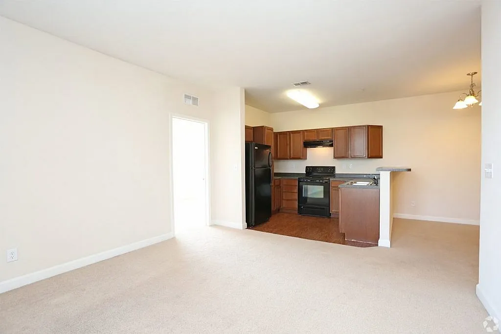Bright and inviting open floor plan with a modern kitchen featuring sleek appliances and warm wooden cabinets, perfect for comfortable living and entertaining.