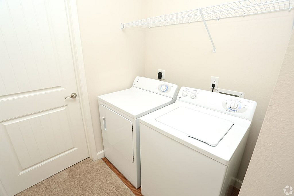 Bright laundry room featuring a modern washer and dryer set with ample shelving space.