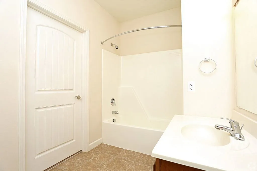 Bright and modern bathroom featuring a sleek countertop sink, large mirror, and spacious bathtub with elegant fixtures.