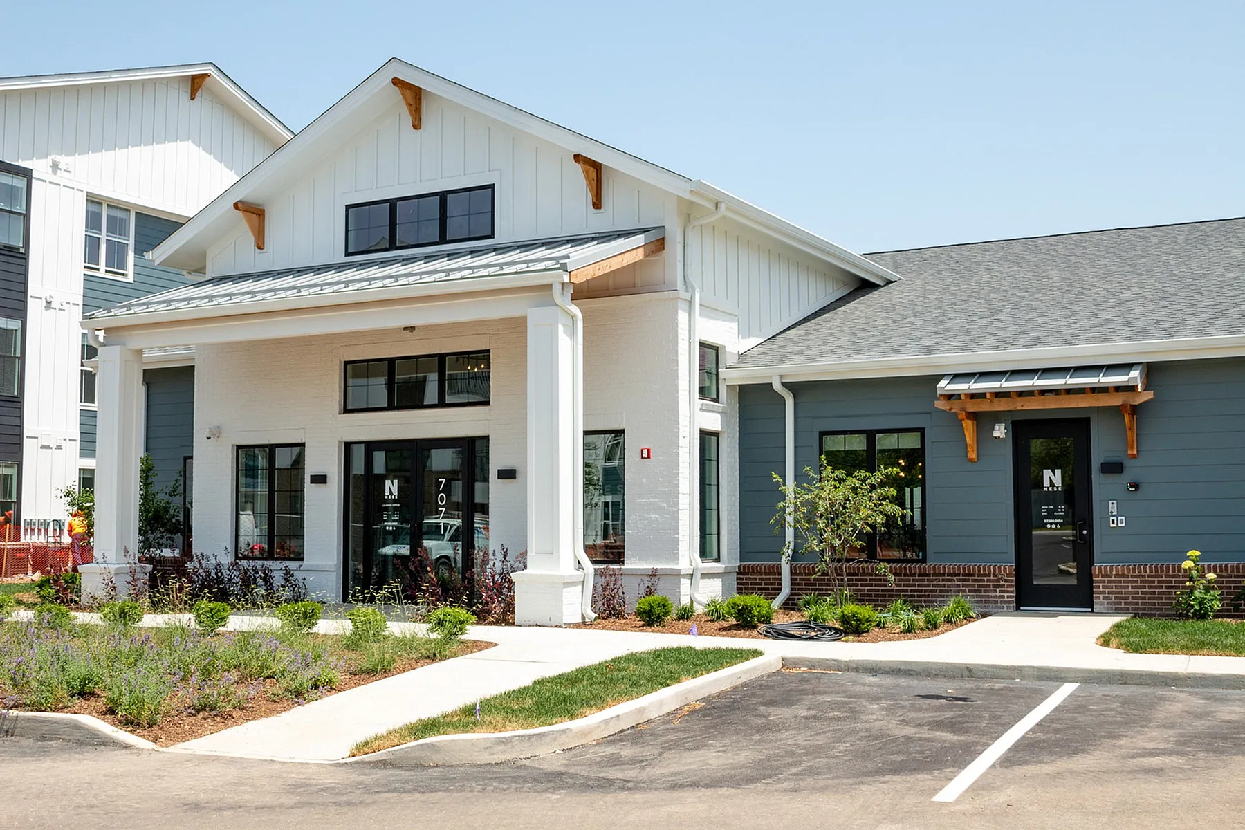 Charming modern building exterior with elegant porch and well-manicured landscaping, featuring large windows and inviting entryways.