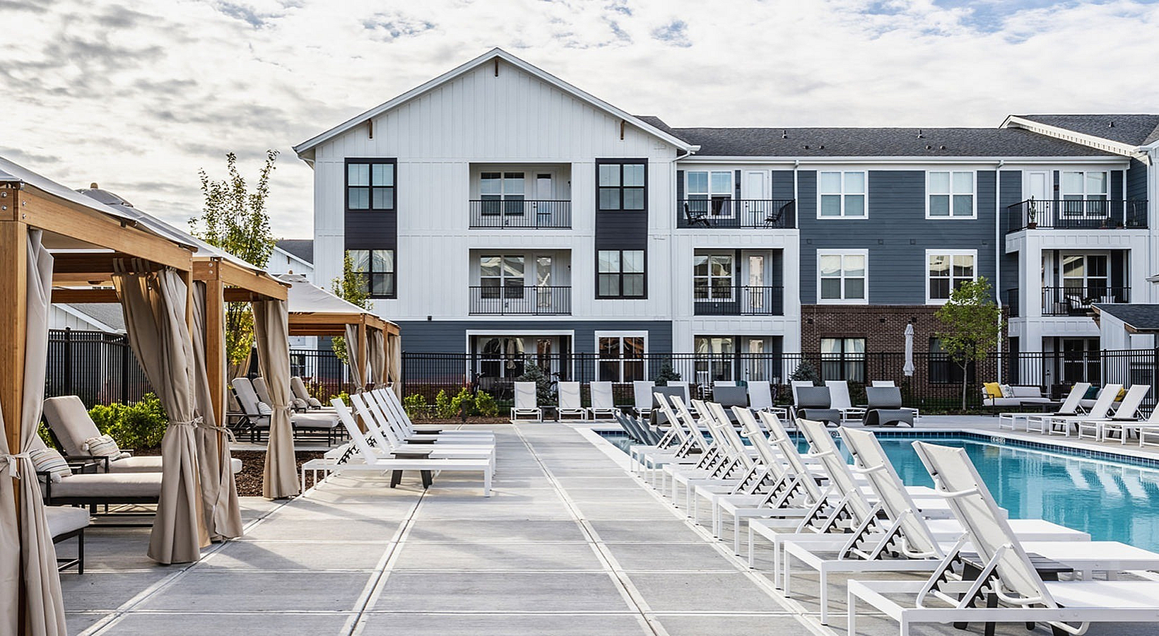 Modern apartment complex with elegant poolside loungers and luxurious cabanas, offering a perfect blend of comfort and style.