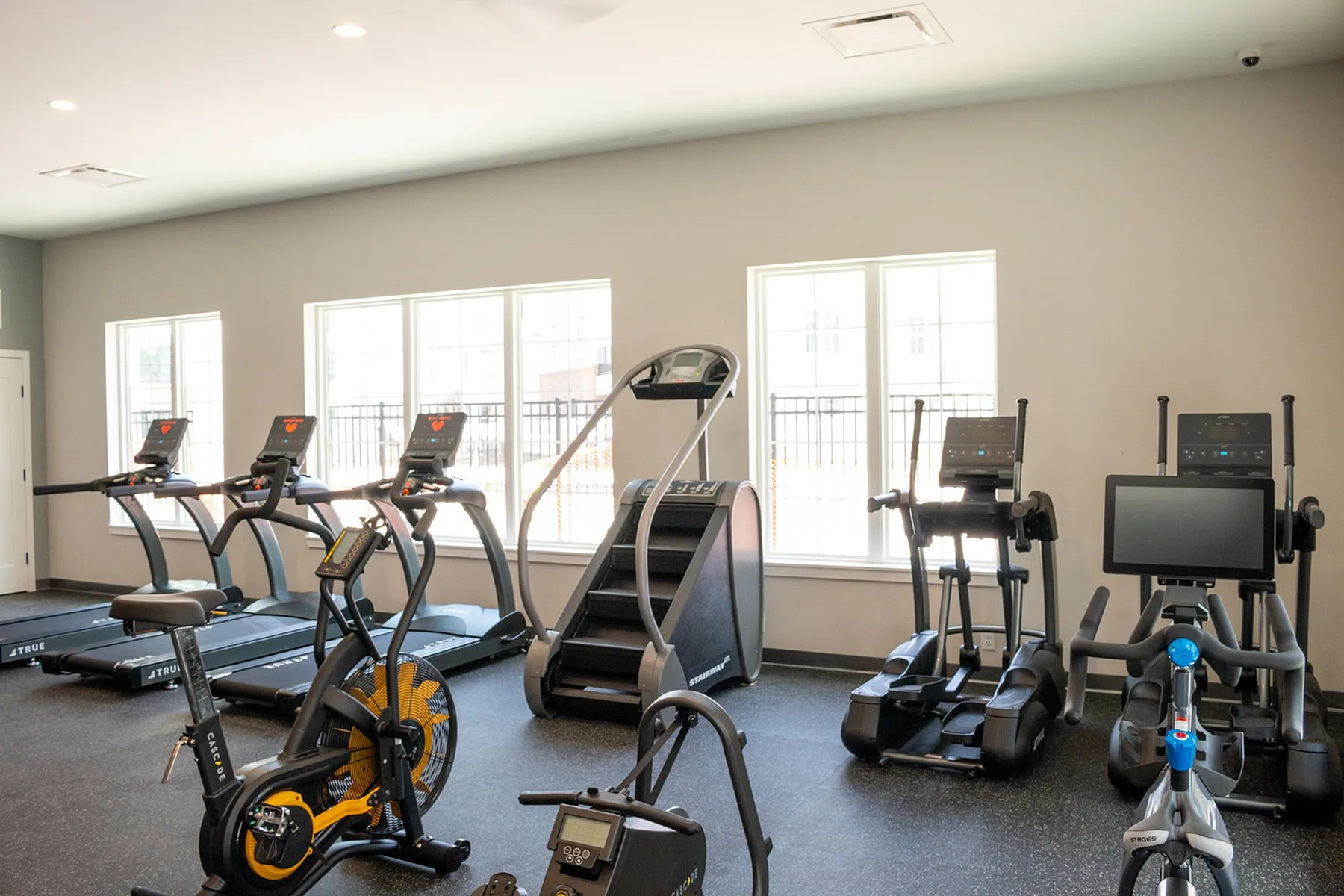 Modern apartment gym with state-of-the-art cardio equipment and ample natural light for an energizing workout experience.
