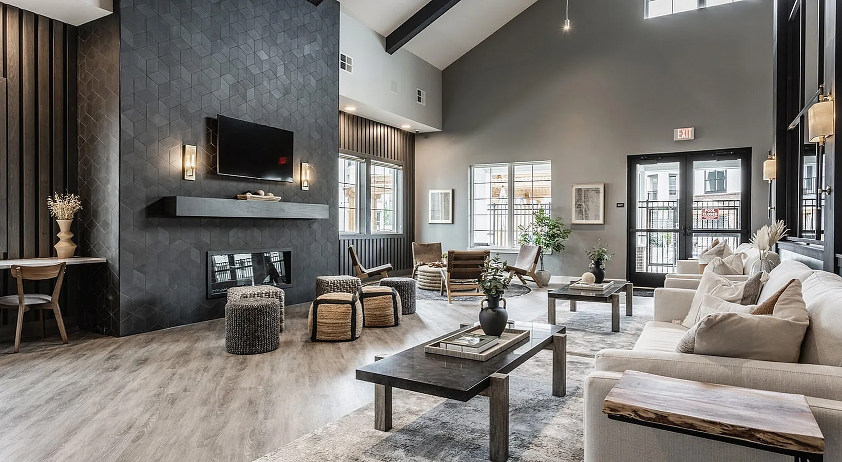Modern living room with high ceilings, sleek fireplace, and elegant decor, showcasing abundant natural light and cozy seating areas.