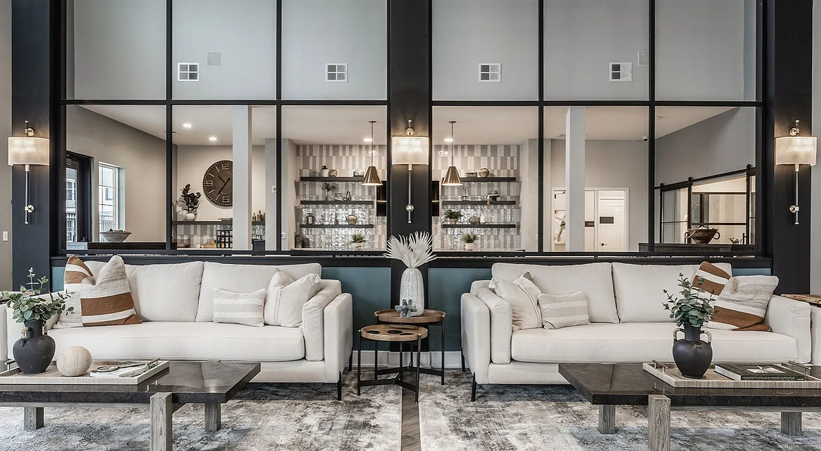 Chic and modern living room with elegant white sofas, plush pillows, and tasteful decor, highlighted by a spacious open view into an inviting kitchen area.