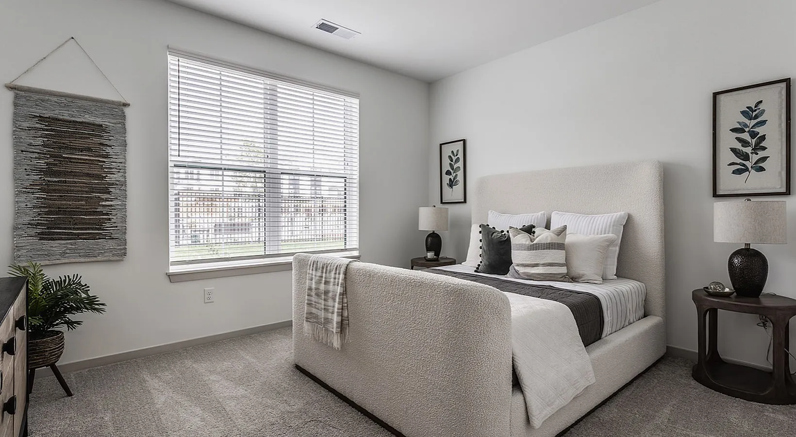 Serene and stylish bedroom with plush carpet, elegant bed, and natural light streaming through large window.
