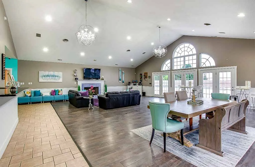 Bright and spacious communal area with stylish chandeliers, large windows, and cozy seating, perfect for gatherings and relaxation.