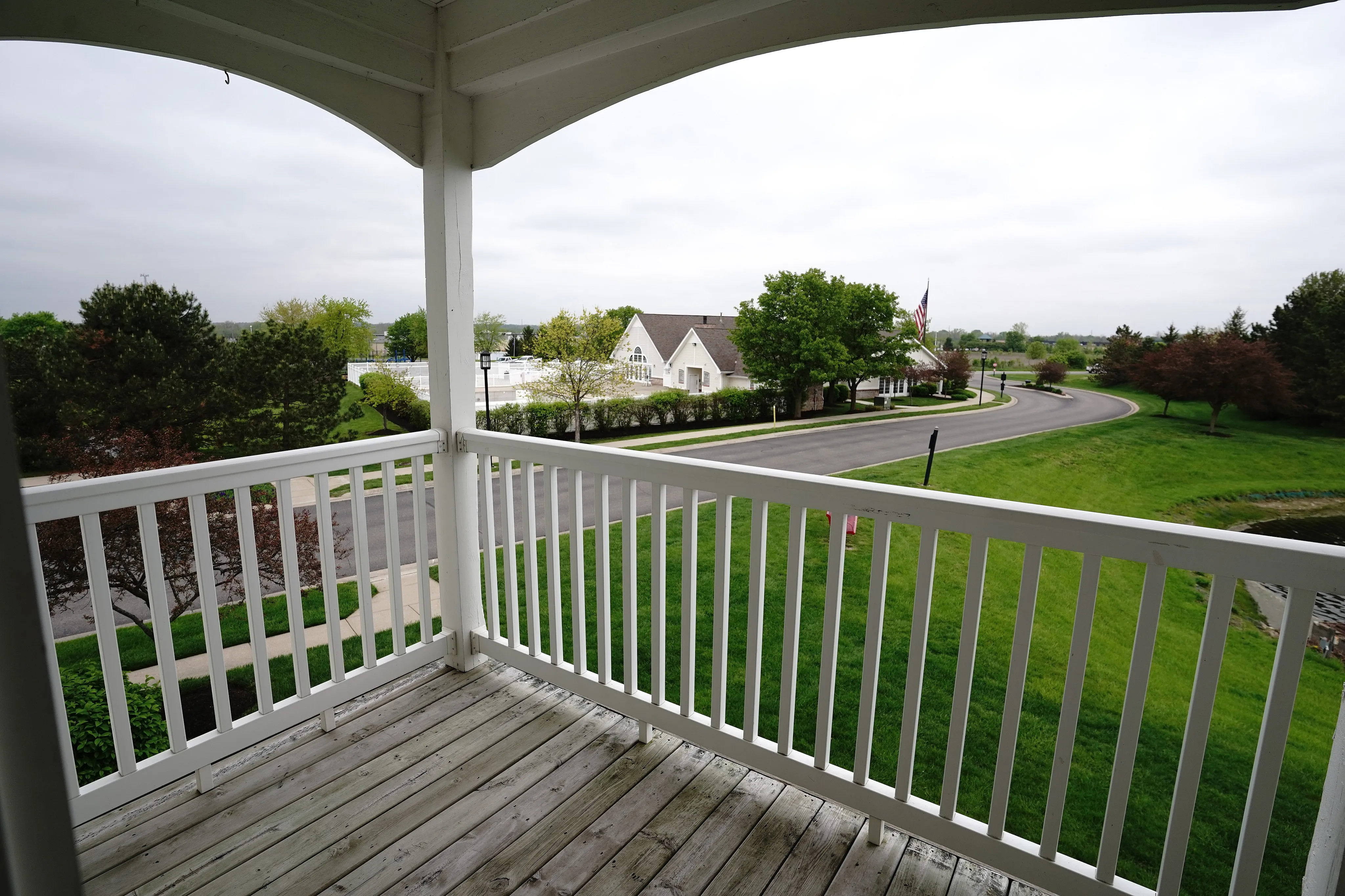 Charming apartment balcony with expansive greenspace views and inviting neighborhood setting.