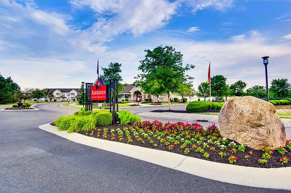 Inviting entrance to Aberdeen Apartments featuring manicured landscaping, vibrant flowers, and a peaceful suburban setting.