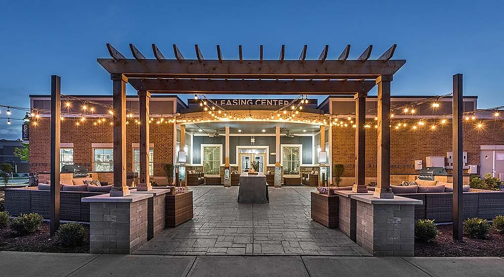 Charming leasing center with inviting string lights, cozy seating areas, and a picturesque pergola.