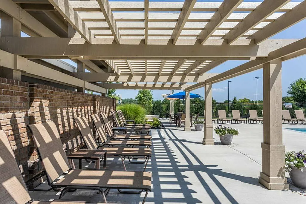 Inviting outdoor patio with sun loungers under a stylish pergola beside a pristine swimming pool, perfect for relaxation and leisure.