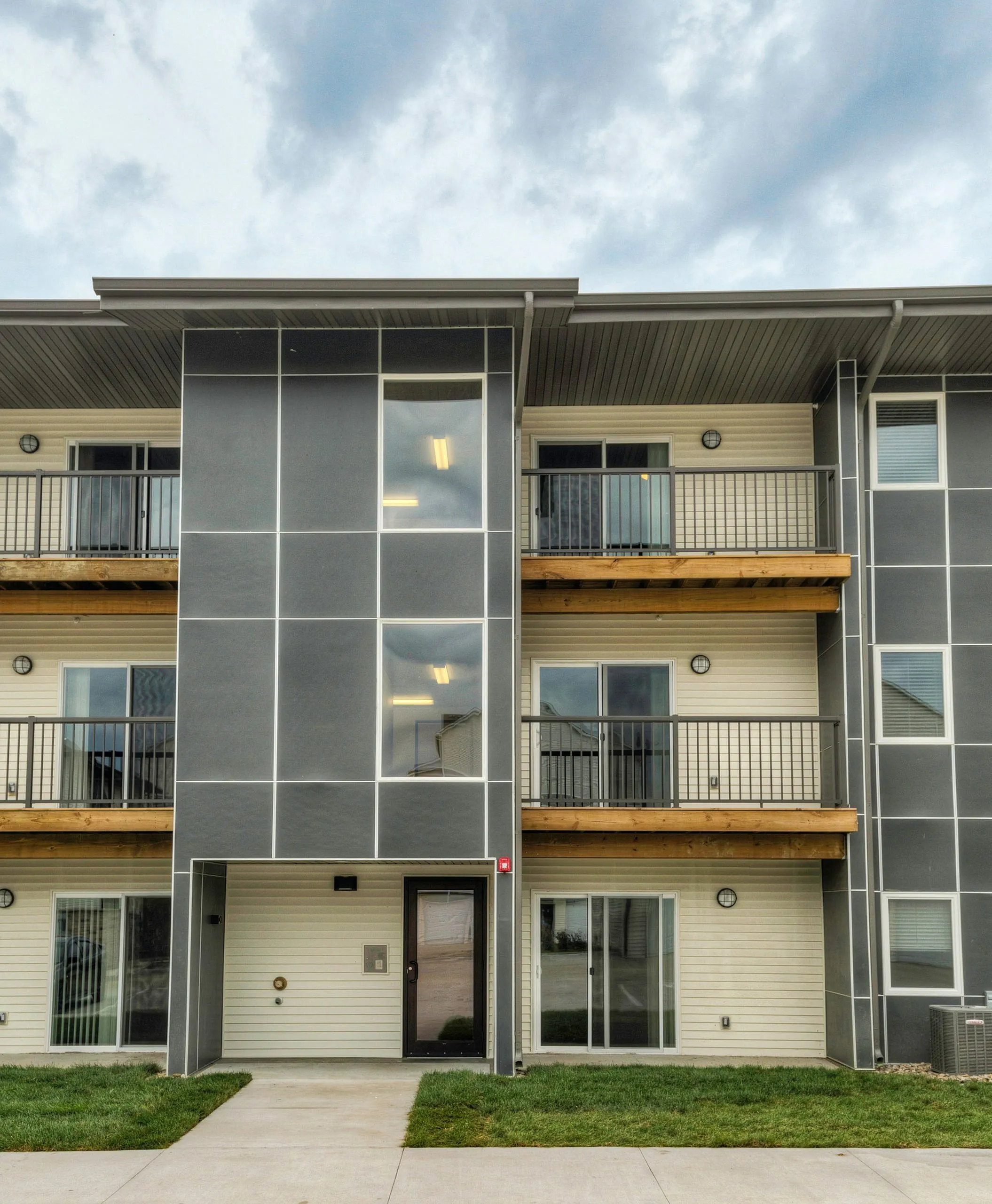 Modern three-story apartment building with stylish balconies and sleek design, perfect for urban living.