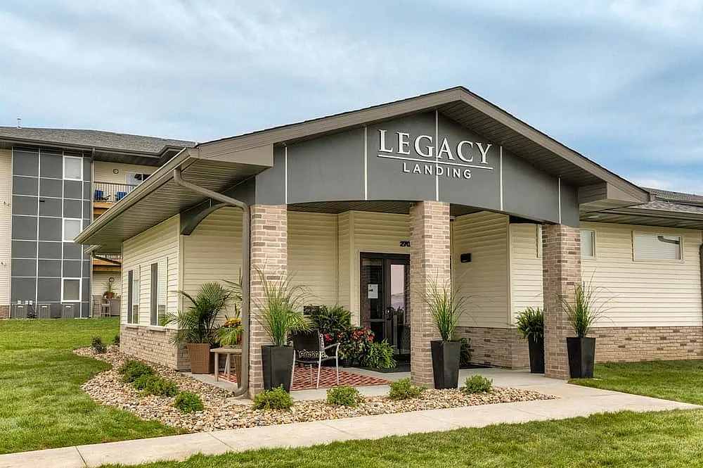 Inviting entrance of Legacy Landing with modern architecture, lush landscaping, and a welcoming ambiance.