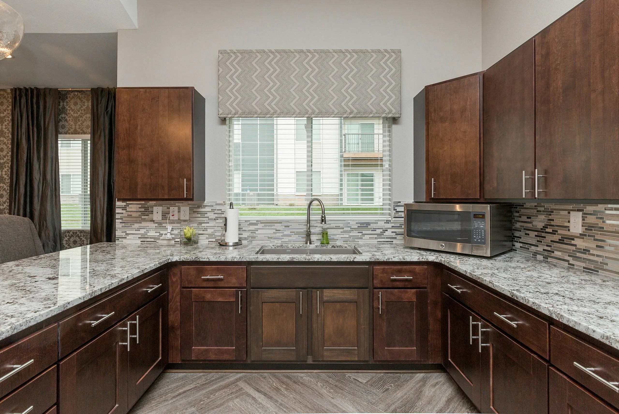 Elegant kitchen with rich wood cabinetry, modern backsplash, and sleek countertops, offering a sophisticated cooking space.