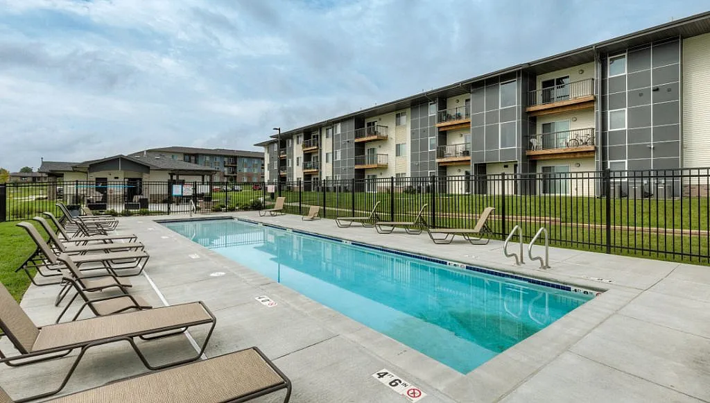 Modern apartment complex with private pool and lounge chairs, offering resort-style living in a serene environment.