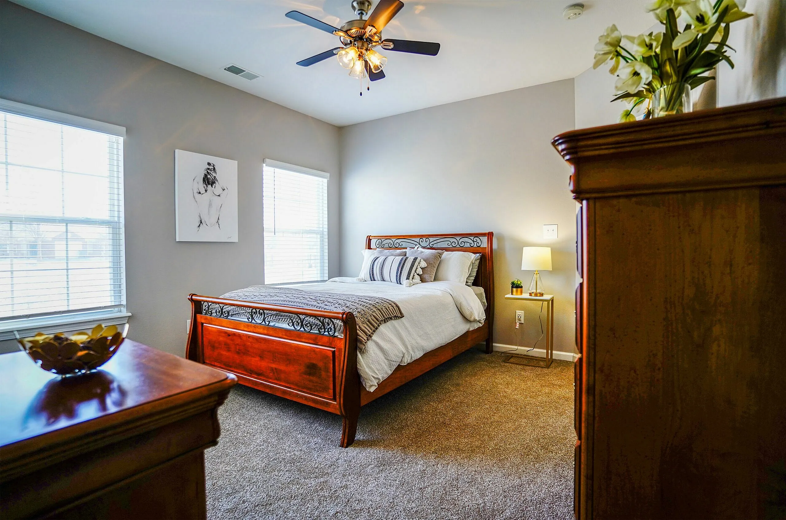 Elegant bedroom featuring a gorgeous wooden bed frame, plush carpeting, and modern decor with ample natural light.