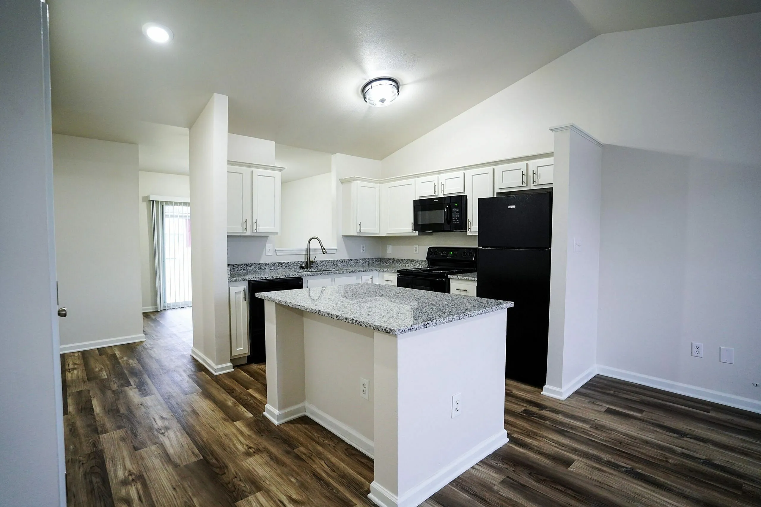 Bright, open kitchen with granite countertops, modern appliances, and elegant wood flooring.