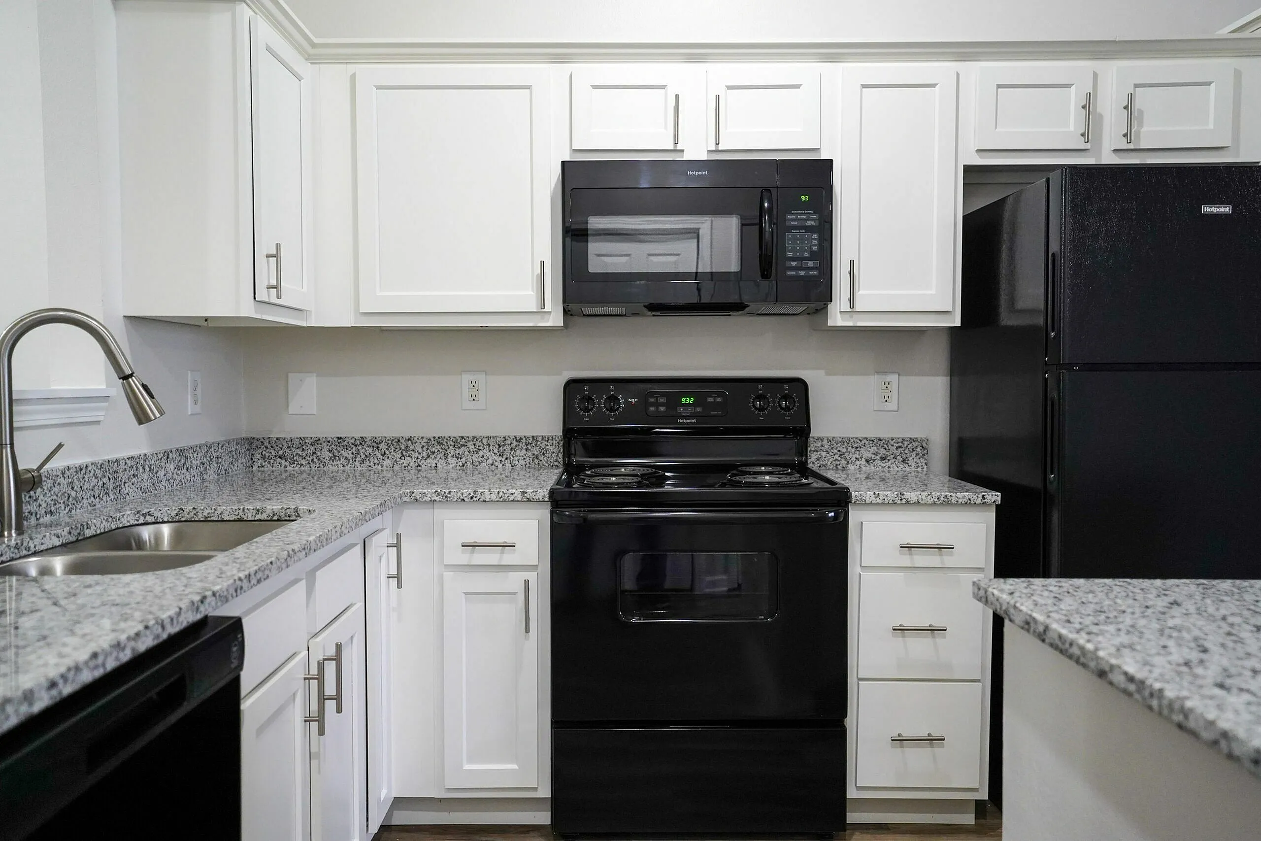 Modern kitchen with sleek black appliances, granite countertops, and elegant white cabinetry offering a stylish cooking experience.
