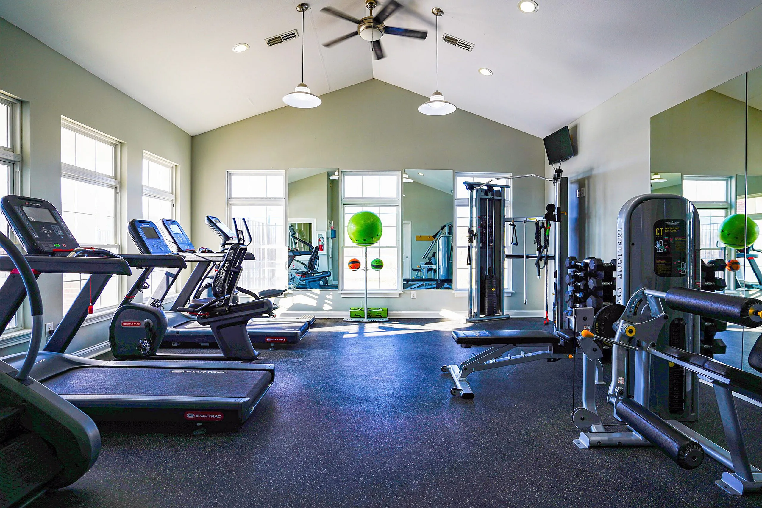 Bright, modern fitness center equipped with state-of-the-art treadmills and weight machines, complemented by large mirrors and natural light.