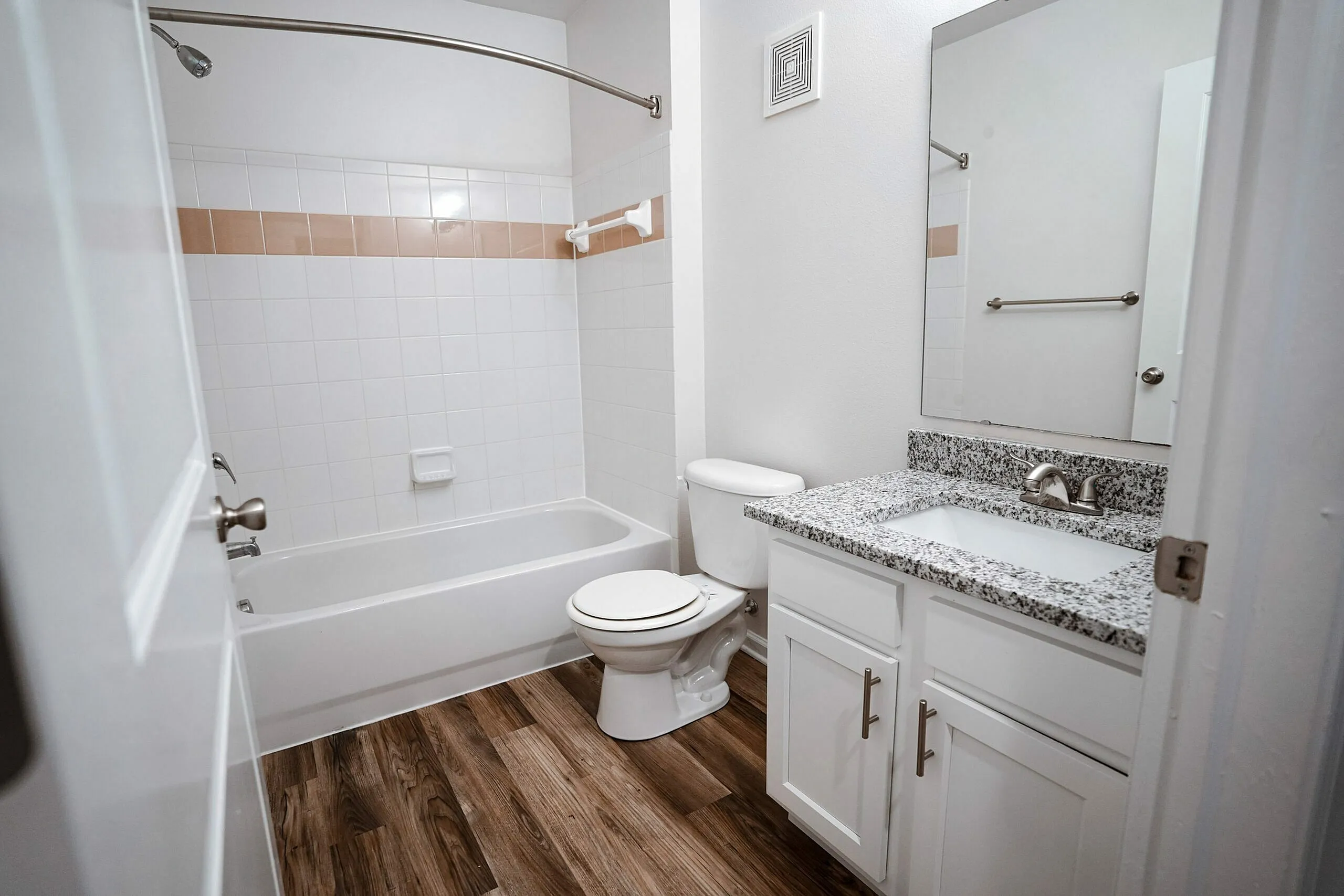 Modern bathroom featuring sleek granite countertops, chic white cabinetry, and elegant wood flooring.