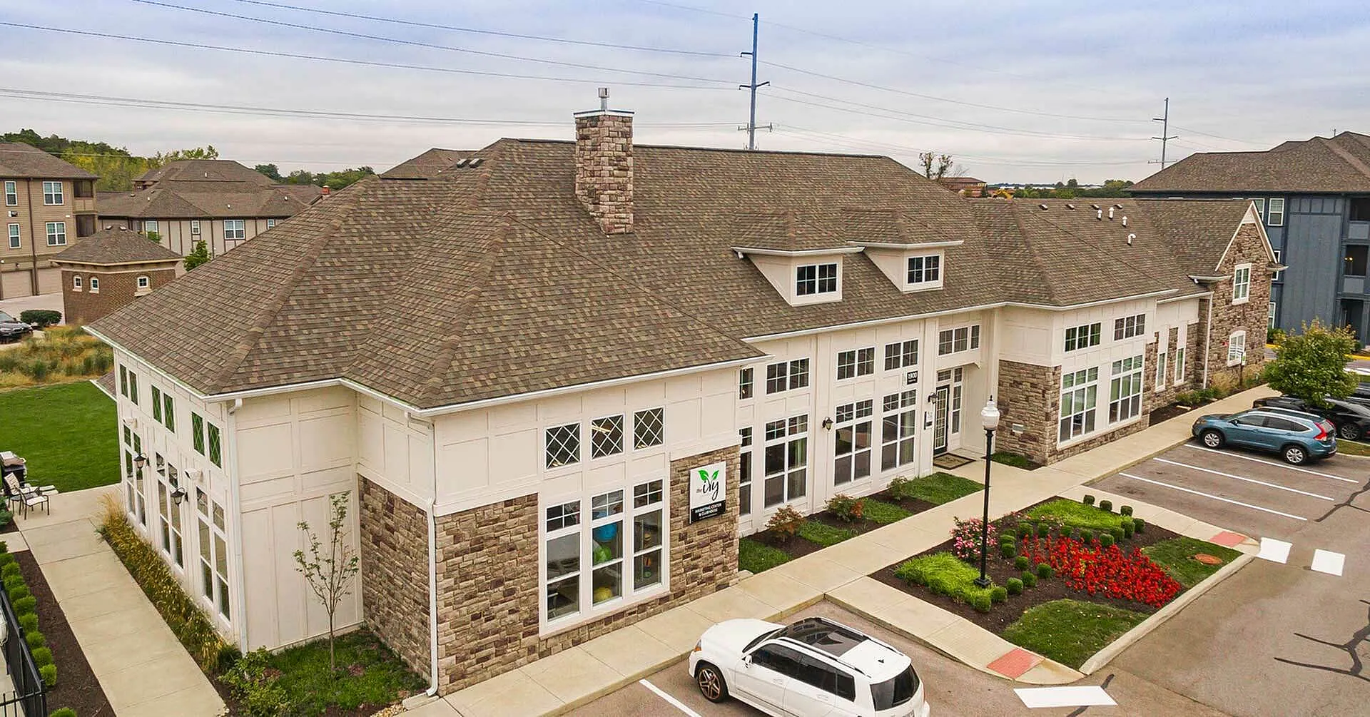Stunning apartment complex with charming stone accents and spacious windows, surrounded by well-maintained landscaping and ample parking.