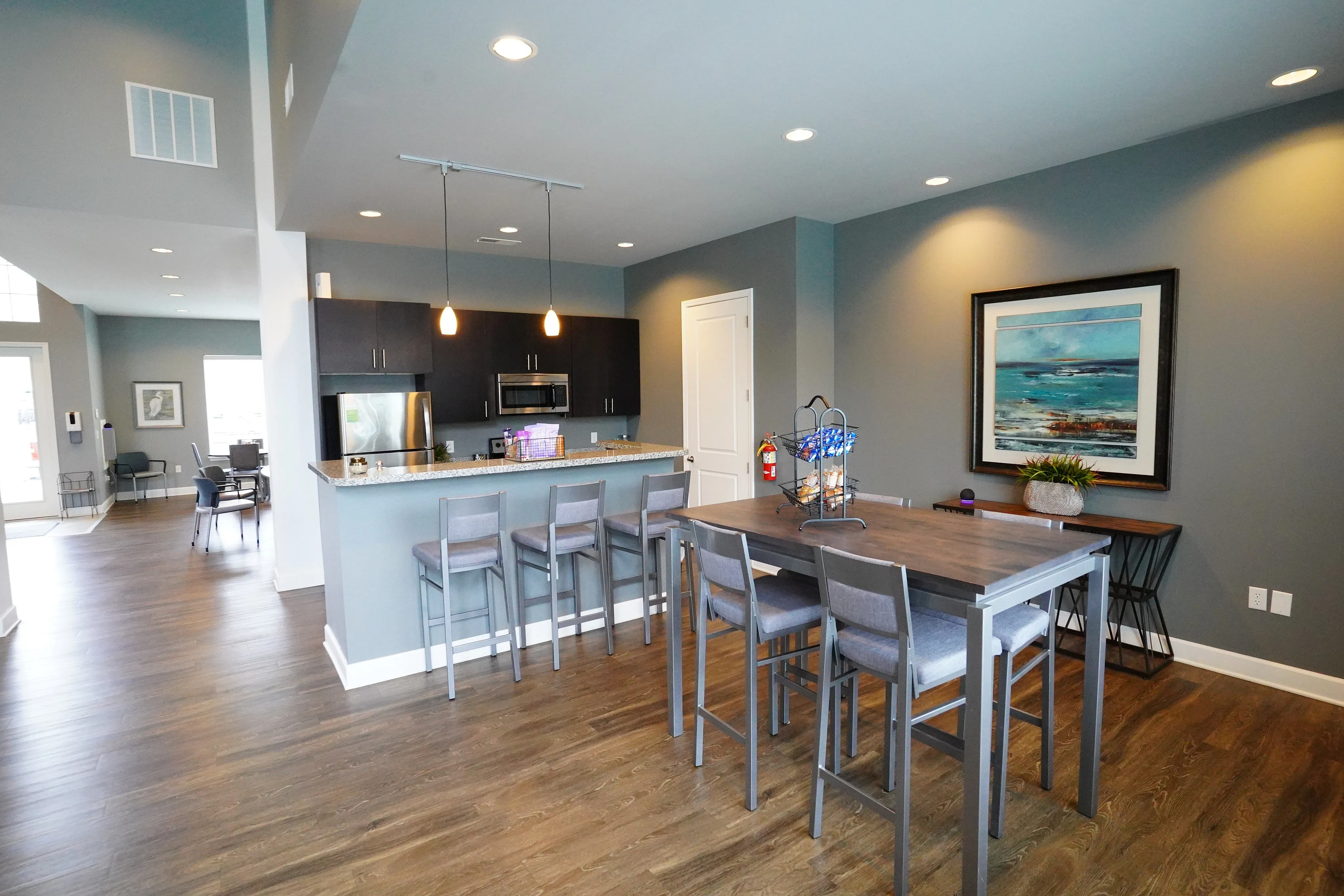 Modern open-concept kitchen and dining area with sleek bar seating, stylish wooden flooring, and elegant lighting fixtures.