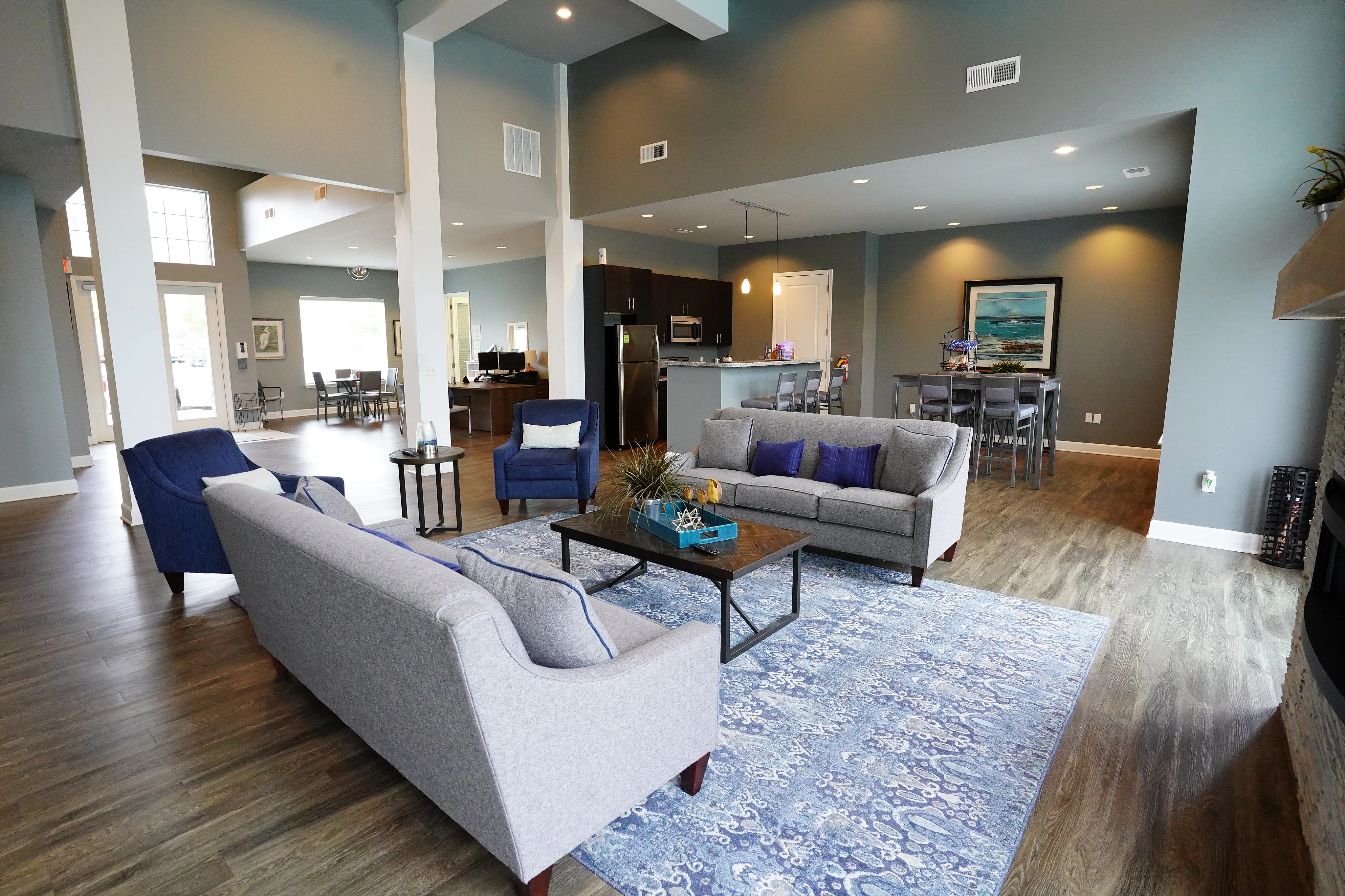 Elegant open-concept living space featuring modern furniture, a cozy seating area, and a stylish kitchen with a dining table, all adorned with beautiful artwork and natural lighting.