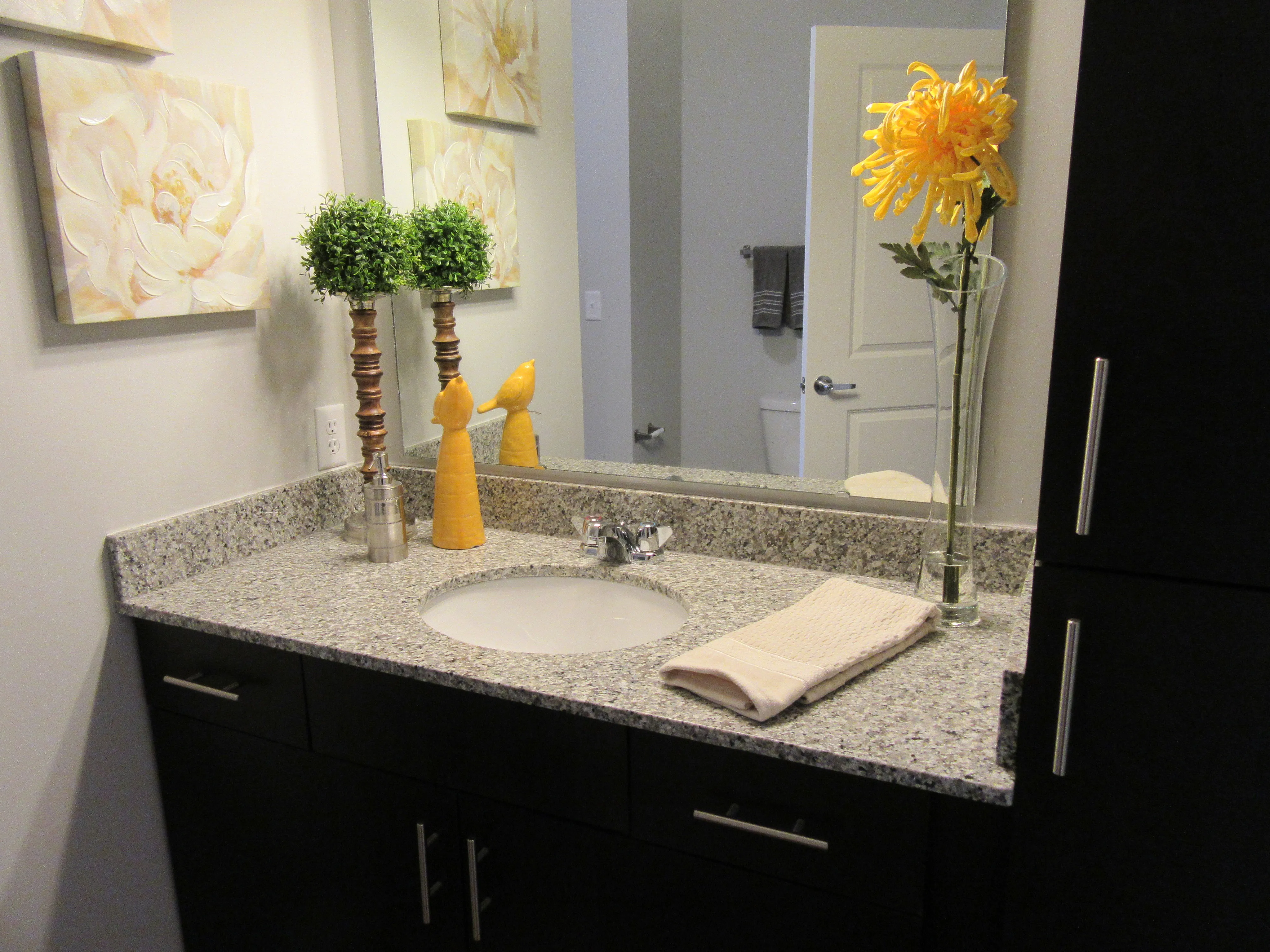 Chic bathroom with granite countertop, elegant decor, and a vibrant yellow floral accent for a stylish touch.