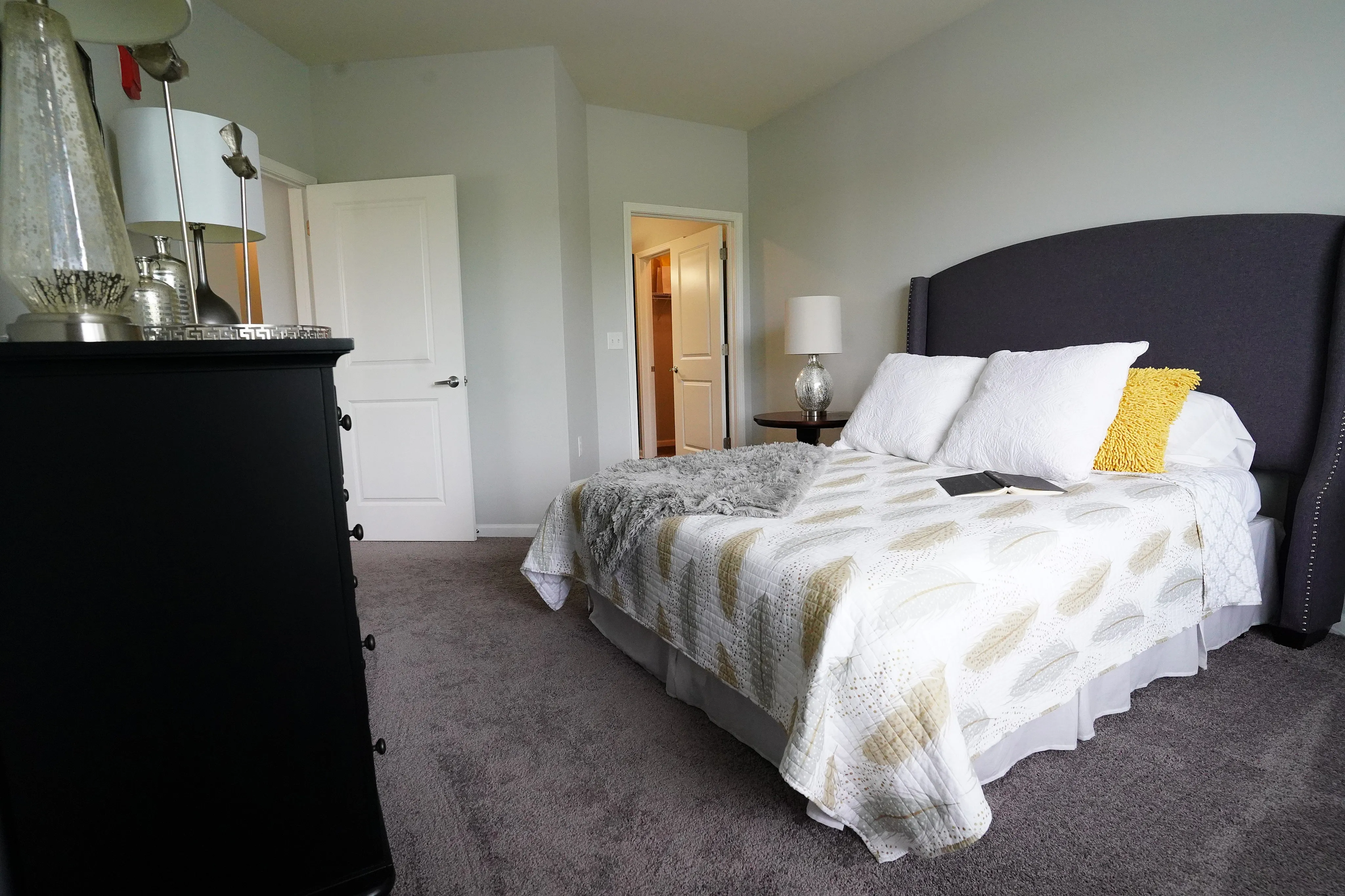 Inviting bedroom with elegant decor, cozy bed draped in soft blankets, and stylish accent lighting, perfect for relaxation.
