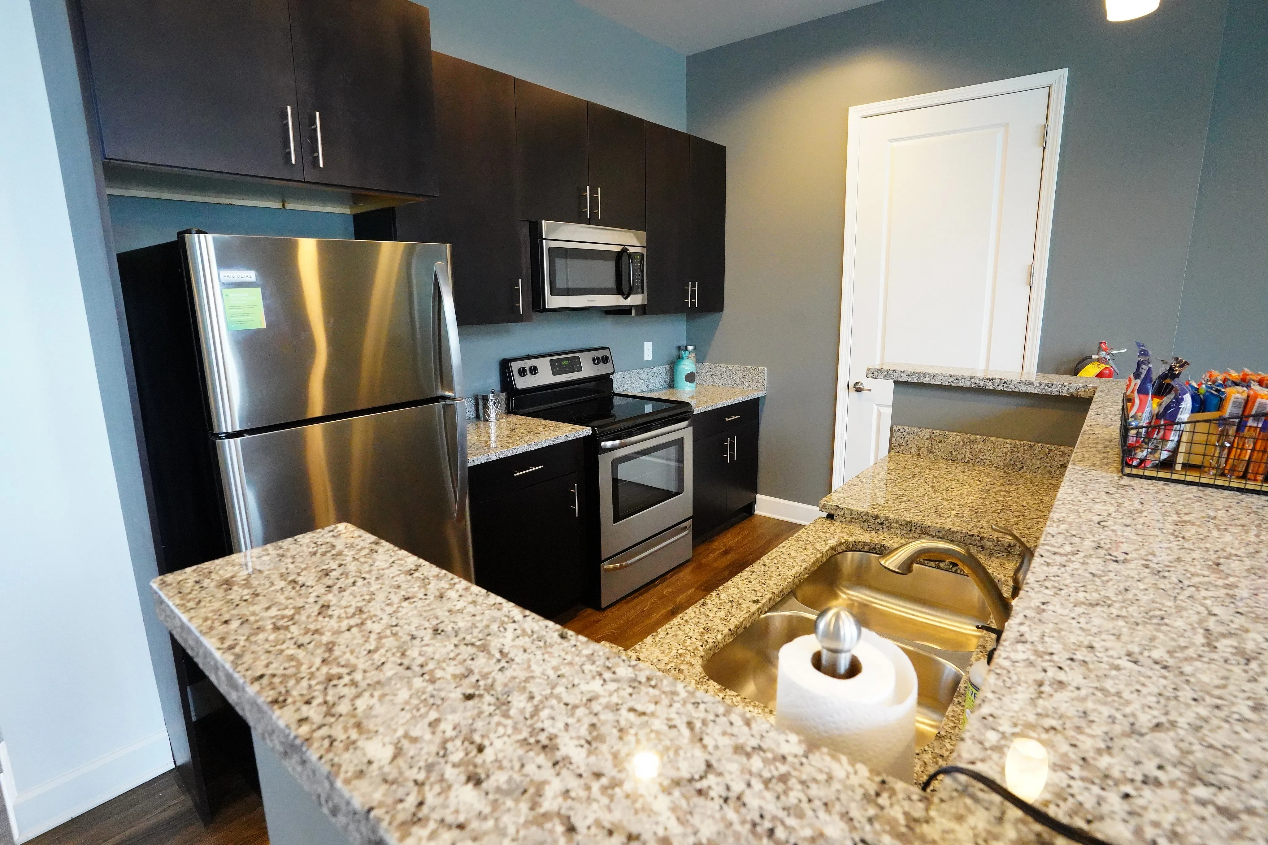 Modern kitchen with sleek stainless steel appliances, elegant granite countertops, and contemporary dark cabinetry, perfect for culinary enthusiasts.