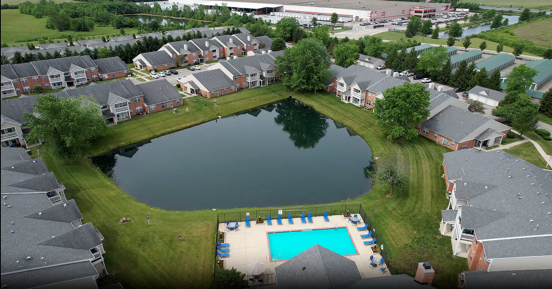 Charming apartment complex with beautiful lake views, expansive green lawns, and a refreshing outdoor pool, perfect for relaxation and recreation.